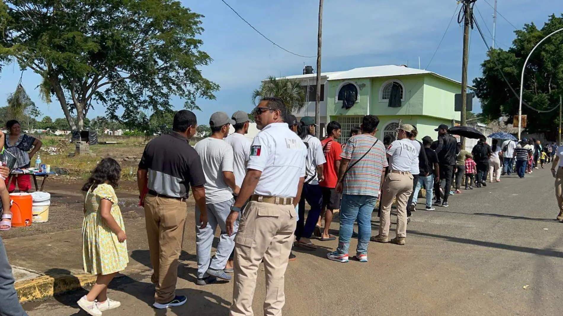 Migrantes haciendo fila en el INM